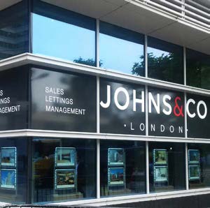 Johns and Co branch window with property details in lit pockets